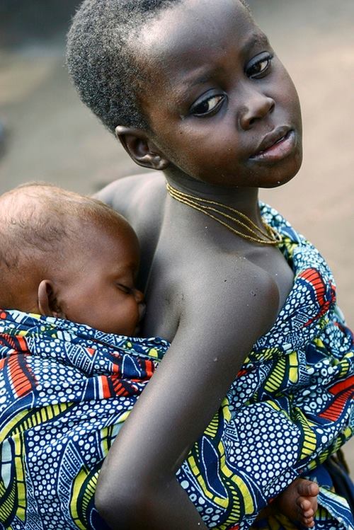 Una niña carga a un bebé en una aldea de la República Democrática del Congo © UN Photo / Martine Perret